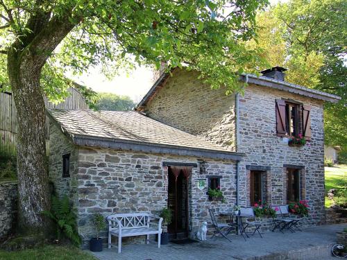 a stone house with tables and chairs in front of it at Attractive Cottage in Baillamont with Terrace in Bièvre