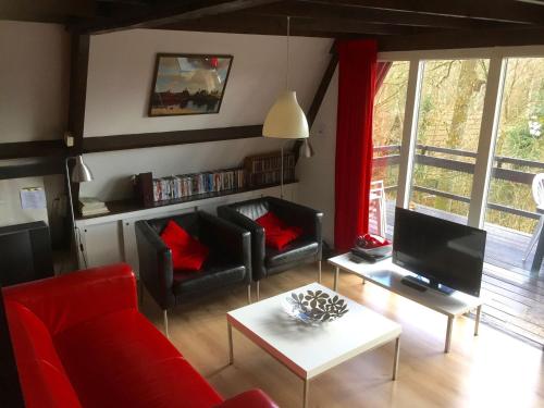een woonkamer met een rode bank en een tv bij Quaint Chalet in Petithan with Roofed Pool in Durbuy