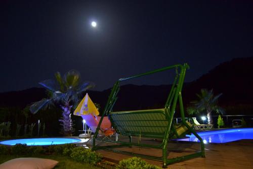 a green chair sitting next to a pool at night at Ada Adrasan Hotel in Adrasan