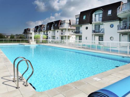 ブレーデネにあるStylish Apartment in Bredene with Poolの一部のアパートメントの建物の前に大きなスイミングプールがあります。