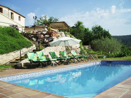 uma piscina com uma mesa e cadeiras e um guarda-sol em Belvilla by OYO Cal Grapiss em La Llacuna