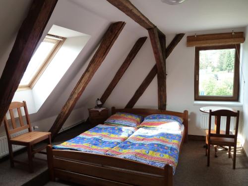 a bedroom with a bed and two chairs and windows at Ubytování Mlýn in Velké Losiny