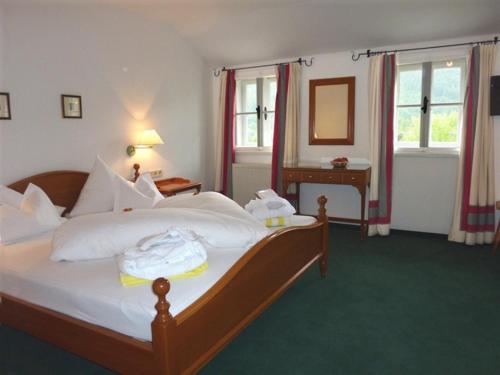 a hotel room with a bed and a desk and windows at Seehotel Enzian in Weissensee