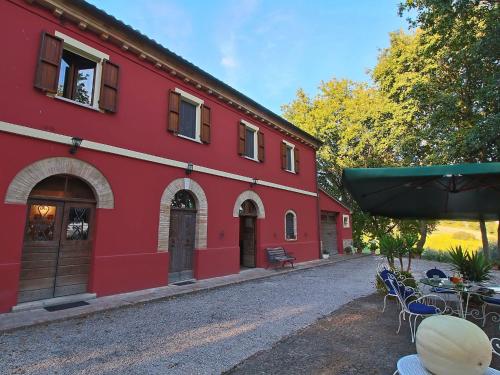 een rood gebouw met tafels en stoelen ervoor bij Belvilla by OYO Casa Lella in Serrungarina