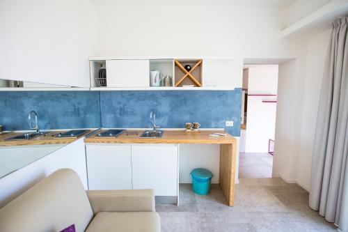 uma cozinha com armários brancos e uma parede azul em A Tonnara em Cefalù