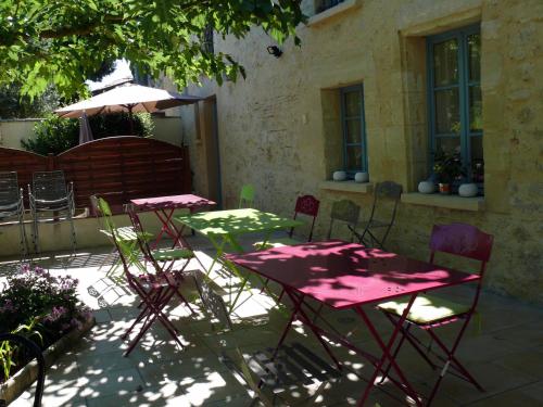 two tables with chairs and an umbrella on a patio at Chambres d'Hôtes du Clos Semper Felix in Sainte-Bazeille