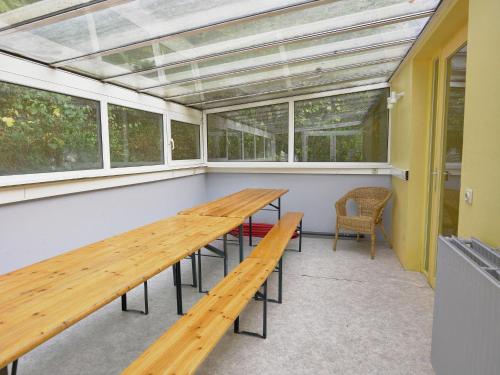 a conservatory with two wooden tables and windows at Spacious Family Home, Sosoye in Sosoye
