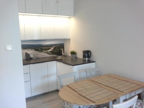 a kitchen with white cabinets and a wooden table at Apartament Podgórze 21 in Szklarska Poręba