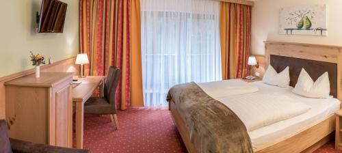 ein Hotelzimmer mit einem großen Bett und einem Schreibtisch in der Unterkunft Landhotel Windlicht in Krombach