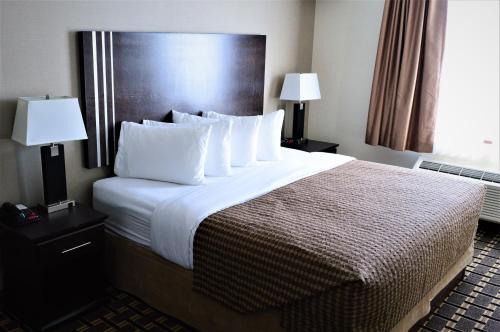 a hotel room with two beds and two lamps at Sigma Inn & Suites in Melville