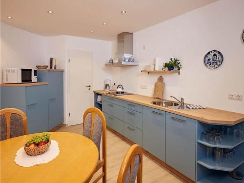 una cocina con armarios azules y una mesa con un bol de fruta en Cosy Holiday Home in Strotzb sch with Sauna en Strotzbüsch