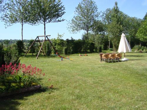 einen Hof mit einer Schaukel und einem Regenschirm in der Unterkunft Rustic holiday home with garden in Normandy in Gouvets