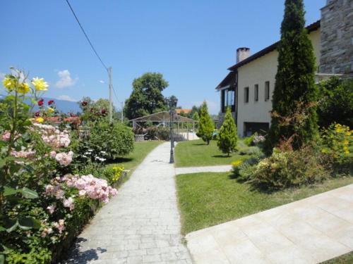 a garden with flowers and a house and a sidewalk at Archontiko Liamas in Stavros