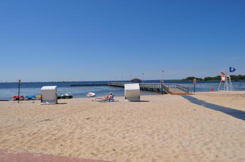 a beach with chairs and people sitting on the sand at Tawerna Panorama in Stepnica