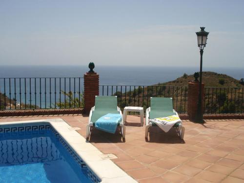 2 sillas de jardín sentadas junto a una piscina en Belvilla by OYO Casa Mirador, en Nerja