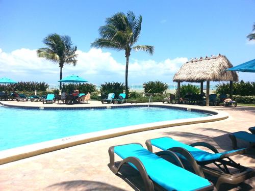 a swimming pool with blue chairs and palm trees at On The Beach - Lux 2 Bedroom Miami in Hollywood