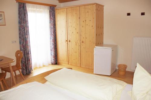 a room with a bed and a refrigerator and a table at Bauernhof Trinkergut in Unternberg