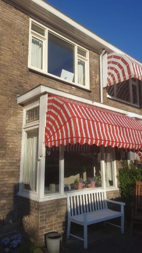 a bench sitting outside of a building with a red awning at Charming Family Home in Delft