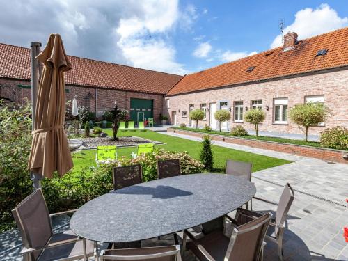 een patio met een tafel en stoelen en een gebouw bij Delightful cottage surrounded by nature in Warneton