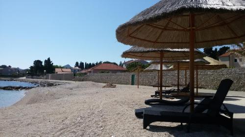 two chairs and an umbrella on a beach at Apartments Elena in Ugljan