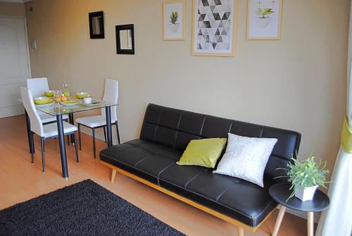 a living room with a black couch and a table at EcoApart Concepción in Concepción