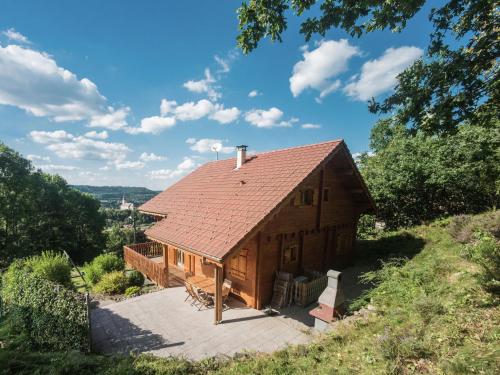 a wooden house with a roof on a hill at Beautiful chalet with sauna and views of Vosges in Anould