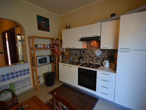 a kitchen with white cabinets and a stove top oven at Belvilla by OYO An apartment near the sea in Finale Ligure