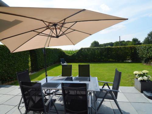 een tafel en stoelen met een grote parasol bij With a broad view over the hilly landscape in Flobecq