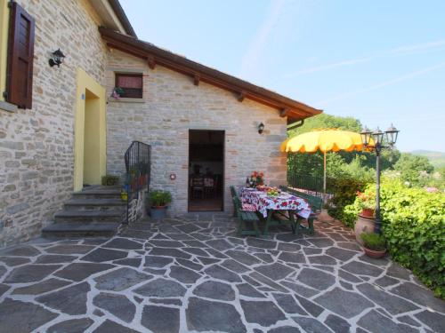 ApecchioにあるStone Cottage in Marche with Swimming Poolのパティオ(テーブル付)、建物の隣に傘