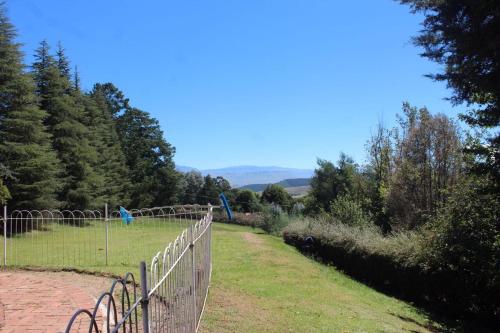 a fence in a field next to a field with trees at Lairds Lodge in Underberg