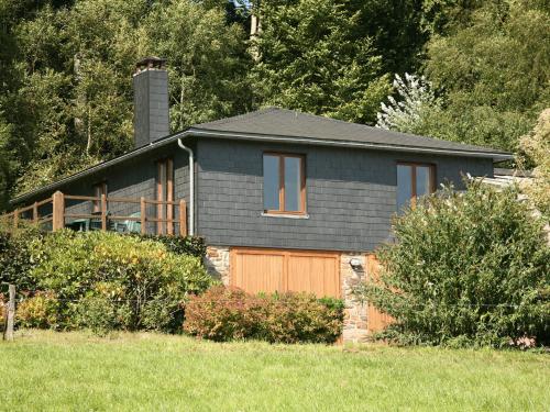 a gray house with a wooden garage in a field at Attached gite on the edge of the forest in Trois-Ponts