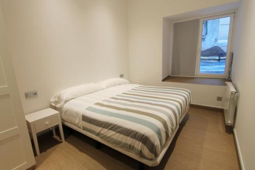a white bedroom with a bed and a window at Jose Maria Soroa in San Sebastián