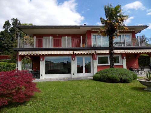 a red house with a balcony and a palm tree at Belvilla by OYO Varese Quattro in Comerio