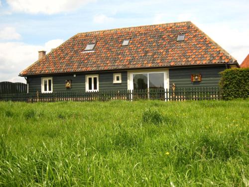 uma casa negra com um telhado vermelho num campo verde em Charming Holiday Home in Zele near the Forest em Zele