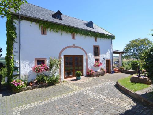 a small white house with a brick driveway at Holiday Home in Ittel with Balcony Heating BBQ Parking in Welschbillig