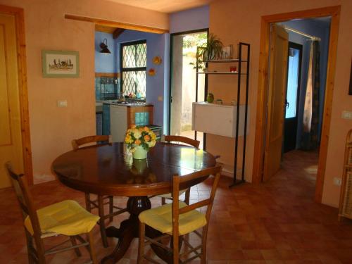 a kitchen and dining room with a wooden table and chairs at Case Vacanze Fossanave in Santa Tecla