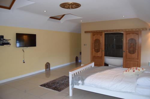 1 dormitorio con 1 cama y TV en la pared en Amazing 4 Bed Scottish Baronial Style House, en Westhill