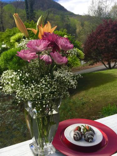 a vase of flowers on a table with a plate of cookies at Grafton Lodge in Lake Lure