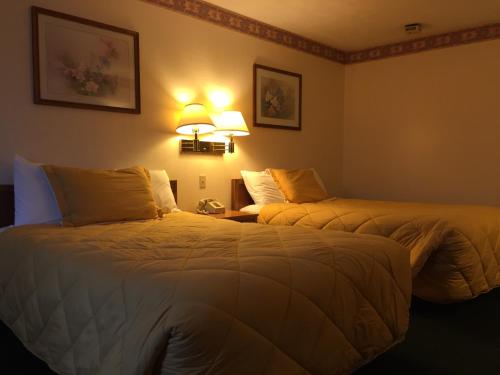 two beds in a hotel room with two lamps at Baxter Inn 4 Less in Baxter Springs