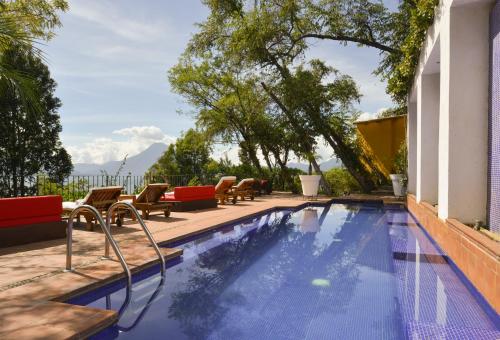 una piscina con sillas, una mesa y un edificio en Hotel Casa Palopo en Santa Catarina Palopó