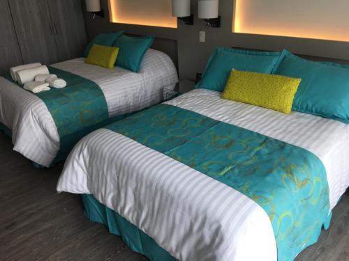 dos camas sentadas una al lado de la otra en una habitación en Herbal Inn Suites en Puebla