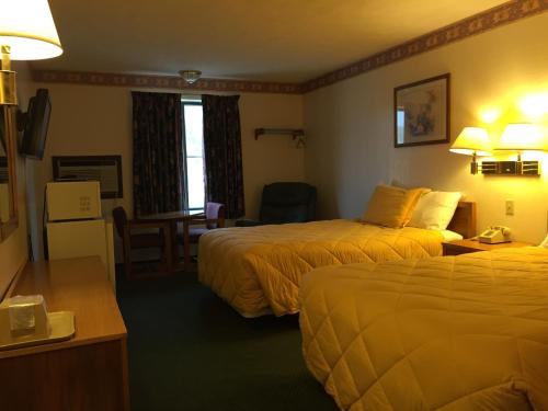 a hotel room with two beds and a desk at Baxter Inn 4 Less in Baxter Springs