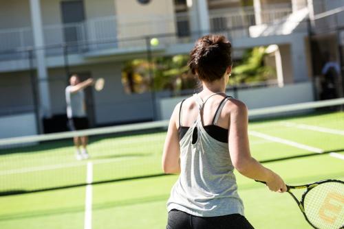 a woman holding a tennis racket on a tennis court at Pier 21 Riverside Apartment Hotel in Fremantle