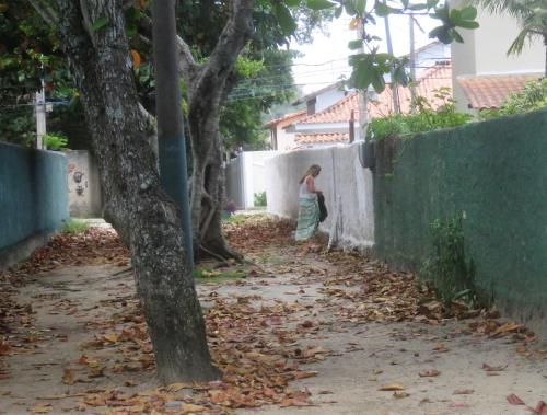 a woman standing against a wall next to a tree at Vila Ebert in Niterói