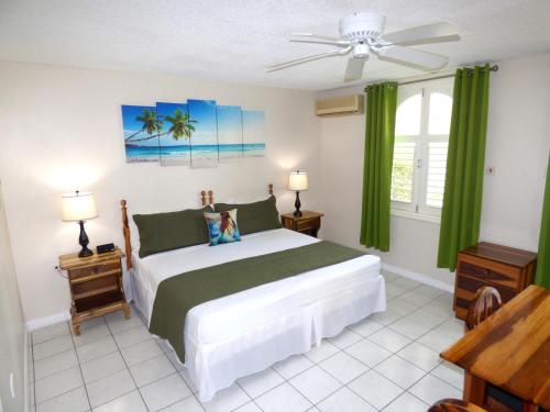 a bedroom with a large bed with green curtains at Beach Studio 6 in Ocho Rios
