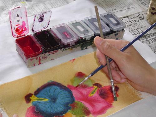 a person painting a bird on a box with brushes at Hotel Murasakimura in Yomitan