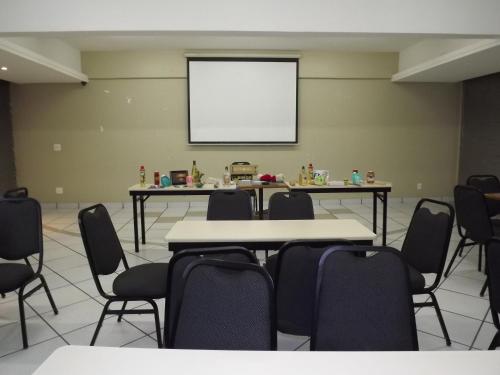 a conference room with tables and chairs and a whiteboard at VOA Plazza Hotel in Águas de Lindóia