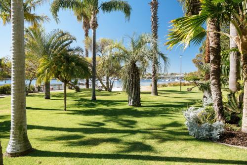 a park with palm trees and a body of water at Pier 21 Riverside Apartment Hotel in Fremantle