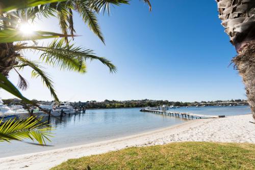a beach with a pier and boats in the water at Pier 21 Riverside Apartment Hotel in Fremantle