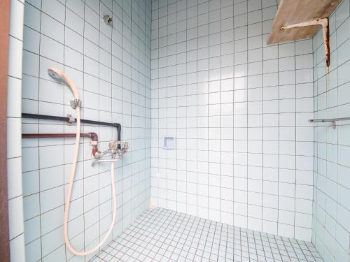 a shower in a bathroom with white tiles at Pension Hoshinosuna in Iriomote